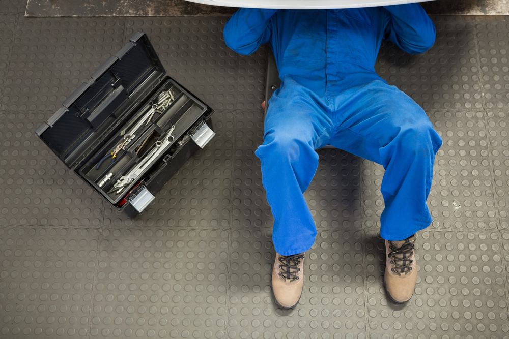 Mechanic lying and working under car at the repair garage