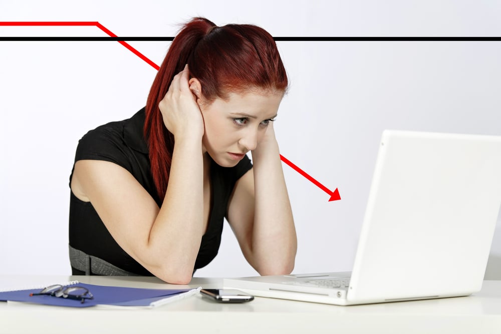 Professional woman showing concern at work using her laptop, displaying a concept graph in decline behind her